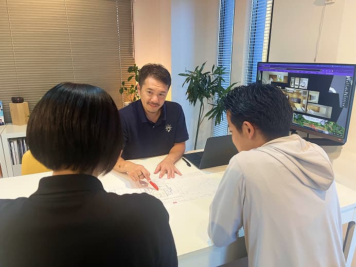 手の上に複数の間取り図が表示されたホワイトボード